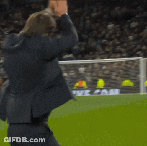 A Man In A Suit Stands On A Soccer Field In Front Of A Heineken Ad GIF