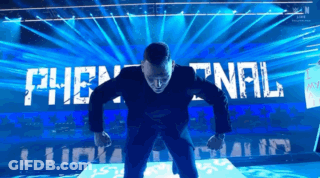 A Man In A Suit Stands On A Stage In Front Of A Sign That Says The Final GIF