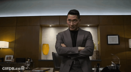 A Man In A Suit Stands With His Arms Crossed In Front Of A Sign That Says Ctv On It GIF