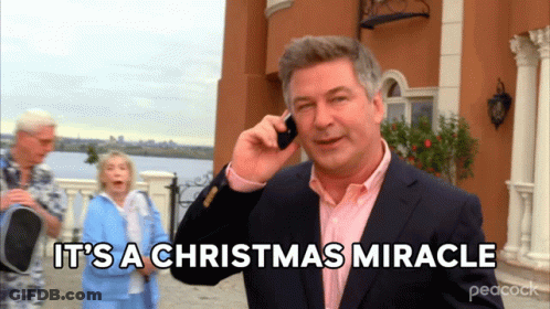 A Man In A Suit Talking On A Cell Phone With The Words It 'S A Christmas Miracle Behind Him GIF