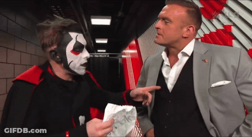 A Man In A Suit Talks To A Man In A Clown Mask GIF