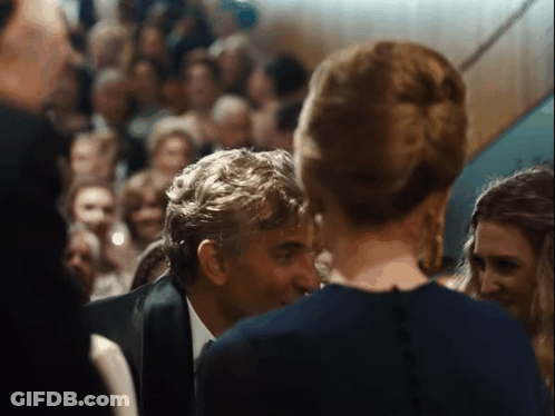 A Man In A Suit Talks To A Woman In A Blue Dress GIF