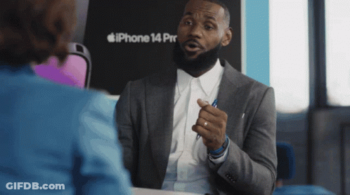 A Man In A Suit Talks To A Woman In Front Of An Iphone 14 Pro GIF