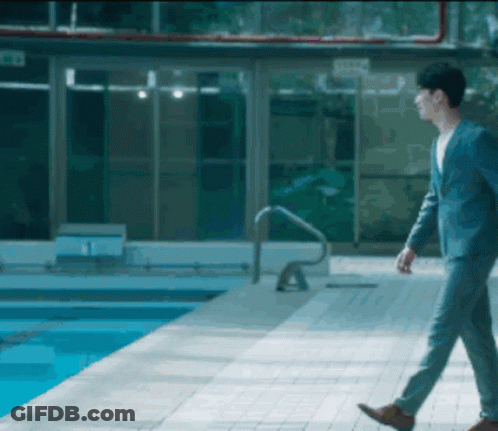 A Man In A Suit Walks By A Pool GIF