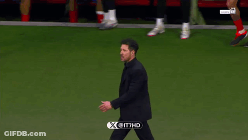 A Man In A Suit Walks On A Soccer Field With A X @ It7hd Logo On The Bottom GIF