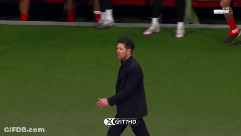 A Man In A Suit Walks On A Soccer Field With A X @ It7hd Logo On The Bottom Right GIF