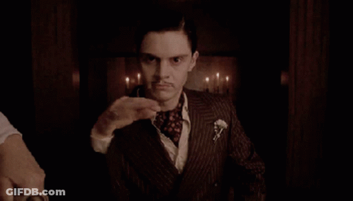 A Man In A Suit With A Mustache Waves His Hand GIF