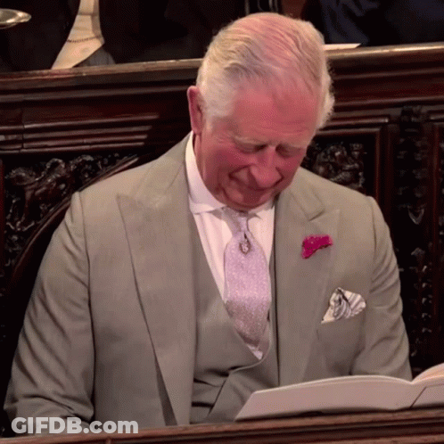 A Man In A Suit With A Pink Pocket Square Is Reading A Book GIF