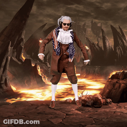 A Man In A Suit With An American Flag Scarf Around His Neck Stands In Front Of A Volcano GIF