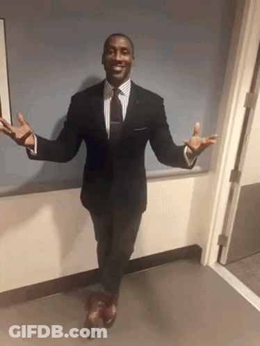 A Man In A Suit With His Arms Outstretched GIF