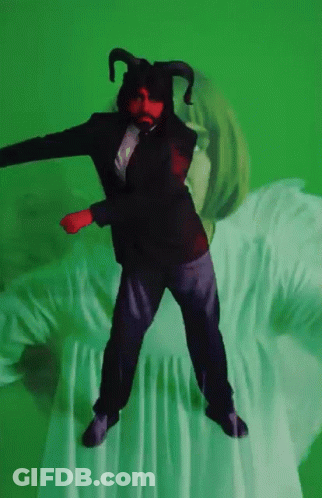 A Man In A Suit With Horns Is Dancing On A Green Background GIF