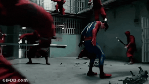 A Man In A Superhero Costume Is Being Attacked By A Group Of Men In Red GIF