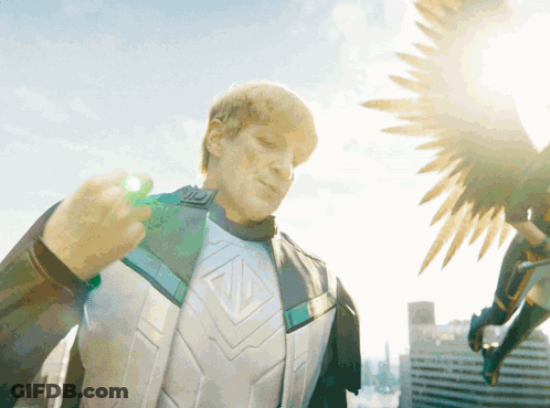 A Man In A Superhero Costume Is Holding A Green Object GIF
