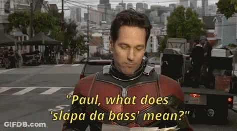 A Man In A Superhero Costume Is Holding A Piece Of Paper And Saying Paul What Does Slapa Da Bass Mean ? GIF