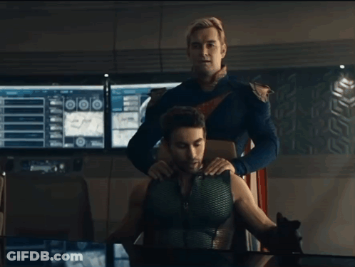 A Man In A Superhero Costume Is Putting His Hand On Another Man 'S Shoulder GIF