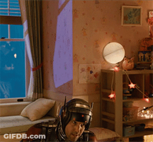 Man In Superhero Costume Sitting On Window Sill GIF
