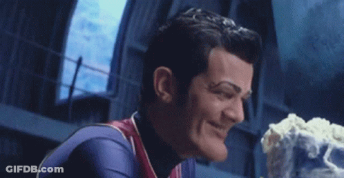 A Man In A Superhero Costume Is Smiling And Holding A Piece Of Cake . GIF
