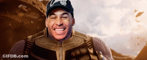A Man In A Superhero Costume Is Smiling While Wearing A Hat With The Letter C On It . GIF