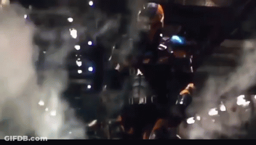 A Man In A Superhero Costume Is Standing In A Dark Room With Smoke Coming Out Of It GIF