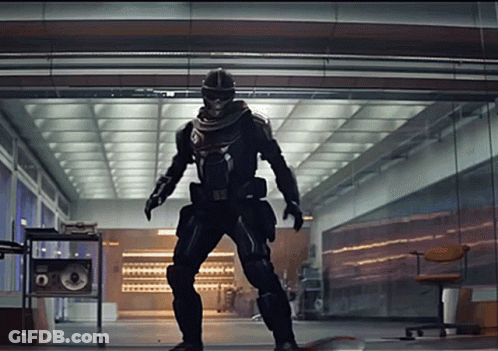 A Man In A Superhero Costume Is Standing In A Hallway GIF