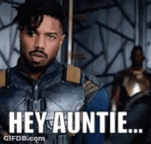 A Man In A Superhero Costume Is Standing In A Room With The Words `` Hey Auntie '' Written On It . GIF