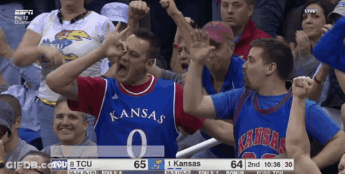 A Man In A Superhero Costume Is Standing In Front Of A Comic Con Sign GIF