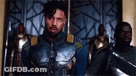 A Man In A Superhero Costume Is Standing In Front Of A Group Of Men . GIF