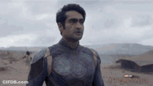 A Man In A Superhero Costume Is Standing In The Desert Looking At Something . GIF
