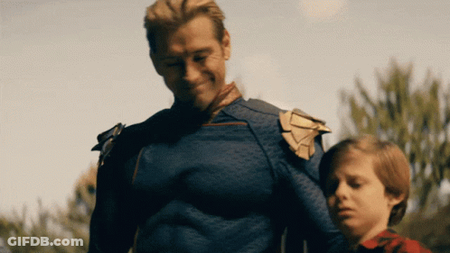 A Man In A Superhero Costume Is Standing Next To A Little Boy GIF