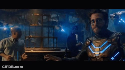 A Man In A Superhero Costume Is Standing Next To A Man In A Tuxedo In A Dark Room . GIF