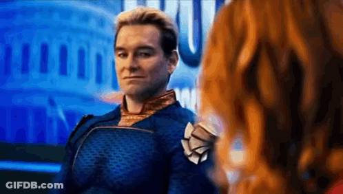 A Man In A Superhero Costume Is Standing Next To A Woman In Front Of A Building . GIF