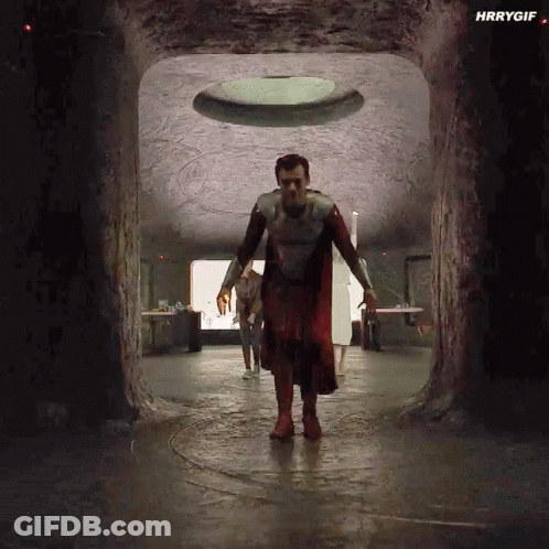 A Man In A Superhero Costume Is Walking Through A Tunnel In A Cave . GIF
