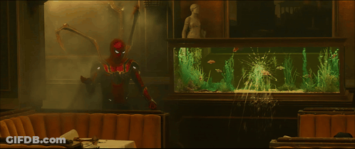 A Man In A Superhero Costume Stands In Front Of A Fish Tank GIF