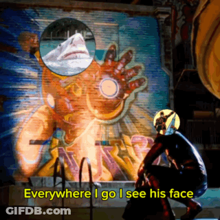 A Man In A Superhero Costume Stands In Front Of A Painting Of Iron Man GIF