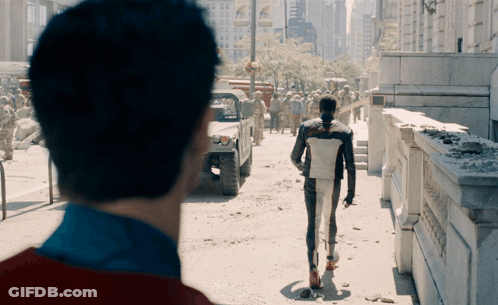 A Man In A Superhero Costume Walks Down A City Street GIF