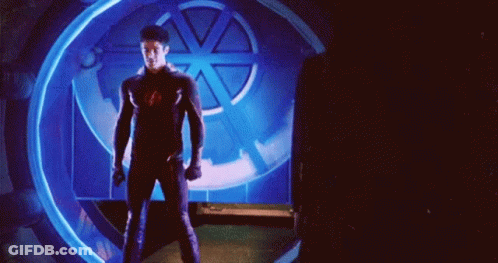 A Man In A Superhero Suit Is Standing In Front Of A Blue Light GIF