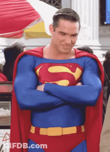 A Man In A Superman Costume Has His Arms Crossed And A Red Cape GIF