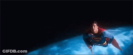 A Man In A Superman Costume Is Flying Through The Air Over A Planet . GIF
