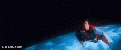 A Man In A Superman Costume Is Flying Through The Air Over A Planet . GIF