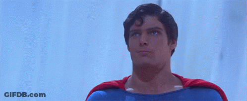 A Man In A Superman Costume Is Giving A Thumbs Up Sign . GIF