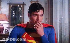 A Man In A Superman Costume Is Holding His Hand To His Mouth GIF
