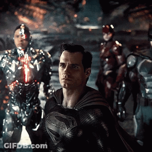 A Man In A Superman Costume Is Standing In Front Of A Group Of Robots GIF