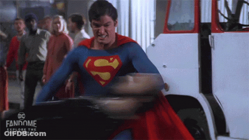 A Man In A Superman Costume Is Standing In Front Of A White Truck .. GIF
