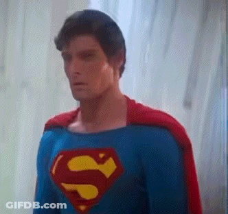 A Man In A Superman Costume Is Standing In Front Of A Window GIF