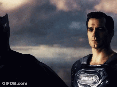 A Man In A Superman Costume Is Standing Next To A Man In A Batman Costume GIF