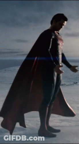 A Man In A Superman Costume Is Standing On A Snowy Field GIF
