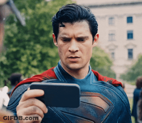A Man In A Superman Costume Is Taking A Picture Of Himself With A Cell Phone GIF