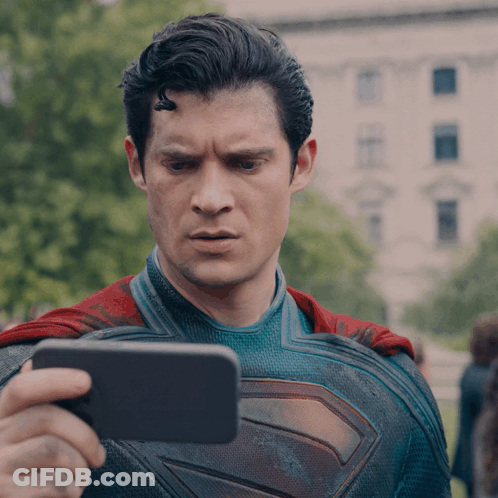 A Man In A Superman Costume Is Taking A Picture Of Himself With A Cell Phone GIF