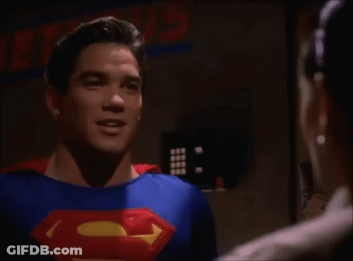 A Man In A Superman Costume Is Talking To Another Man In A Room . GIF
