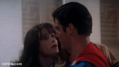 A Man In A Superman Costume Kisses A Woman GIF